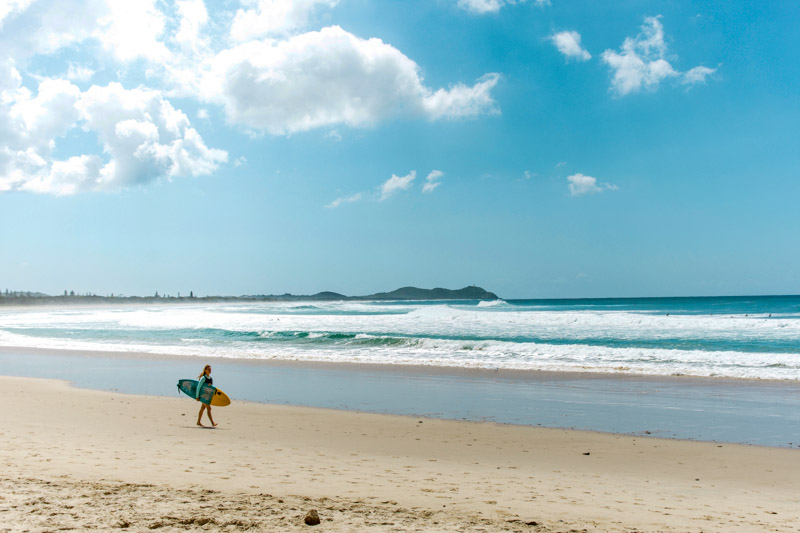 Surfer walking along Broken Head Beach, Byron Bay.