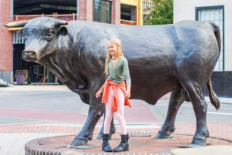 girls tanding beside bull sculpture durham