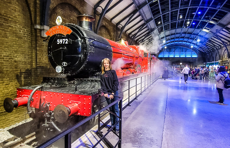 A person standing in front of a train at a train station