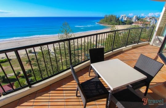 tables and chairs on a balcony next to a beach