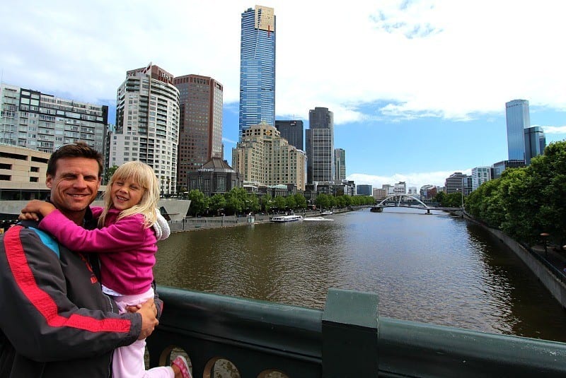 people standing on a bridge with a city behind them