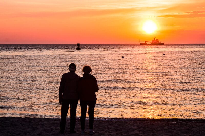 people standing on the beach watching the sunset