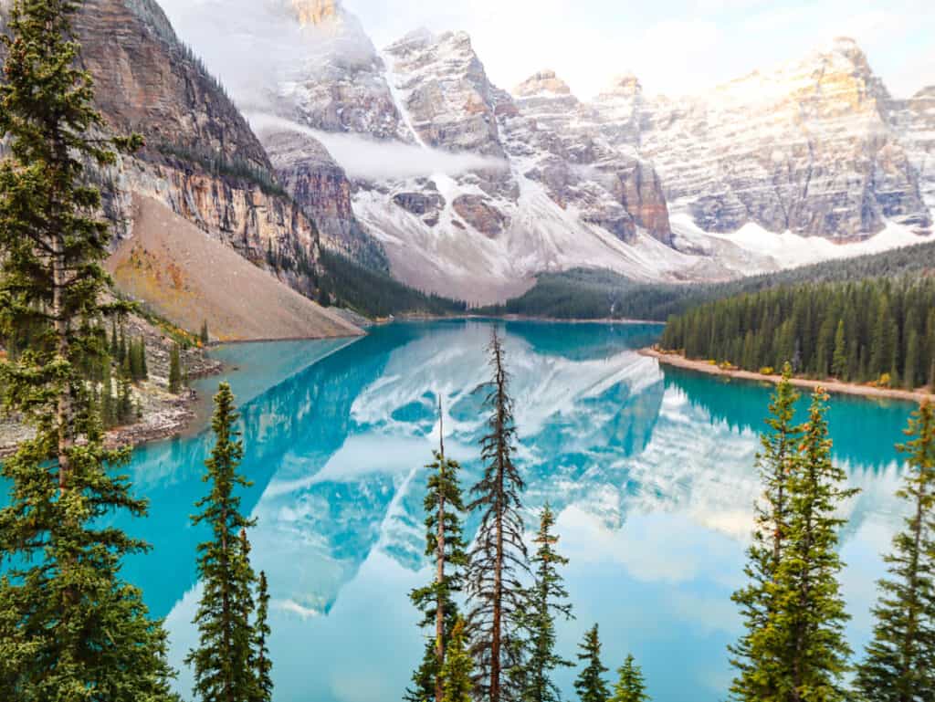 torquoise blue water of moraine lake surrounded by snow capped peaks