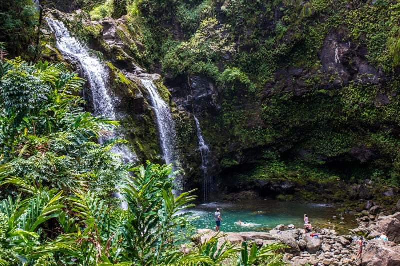 waterfall spilling into pool people swimming in