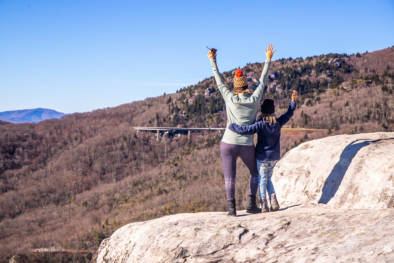 people standing on a boulder in the mountains