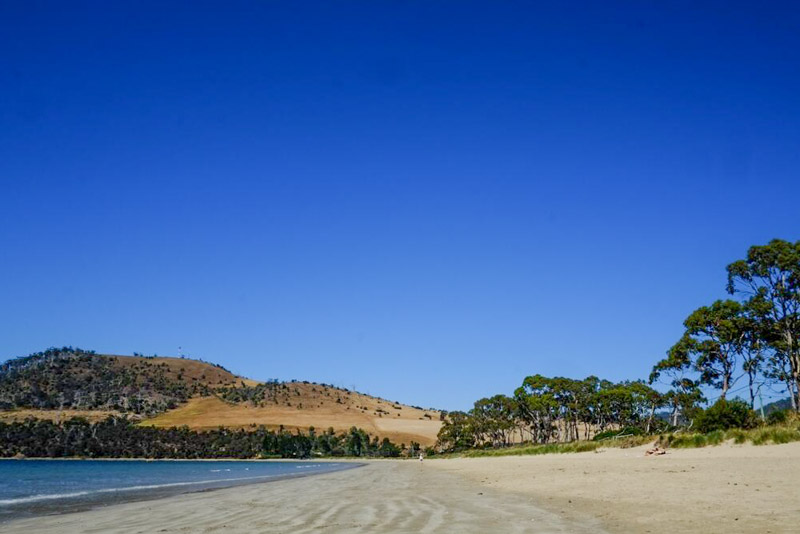 white sand with red hills on edge of beach