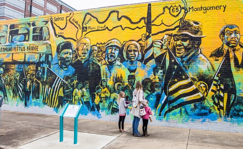 people standing in front of a wall mural